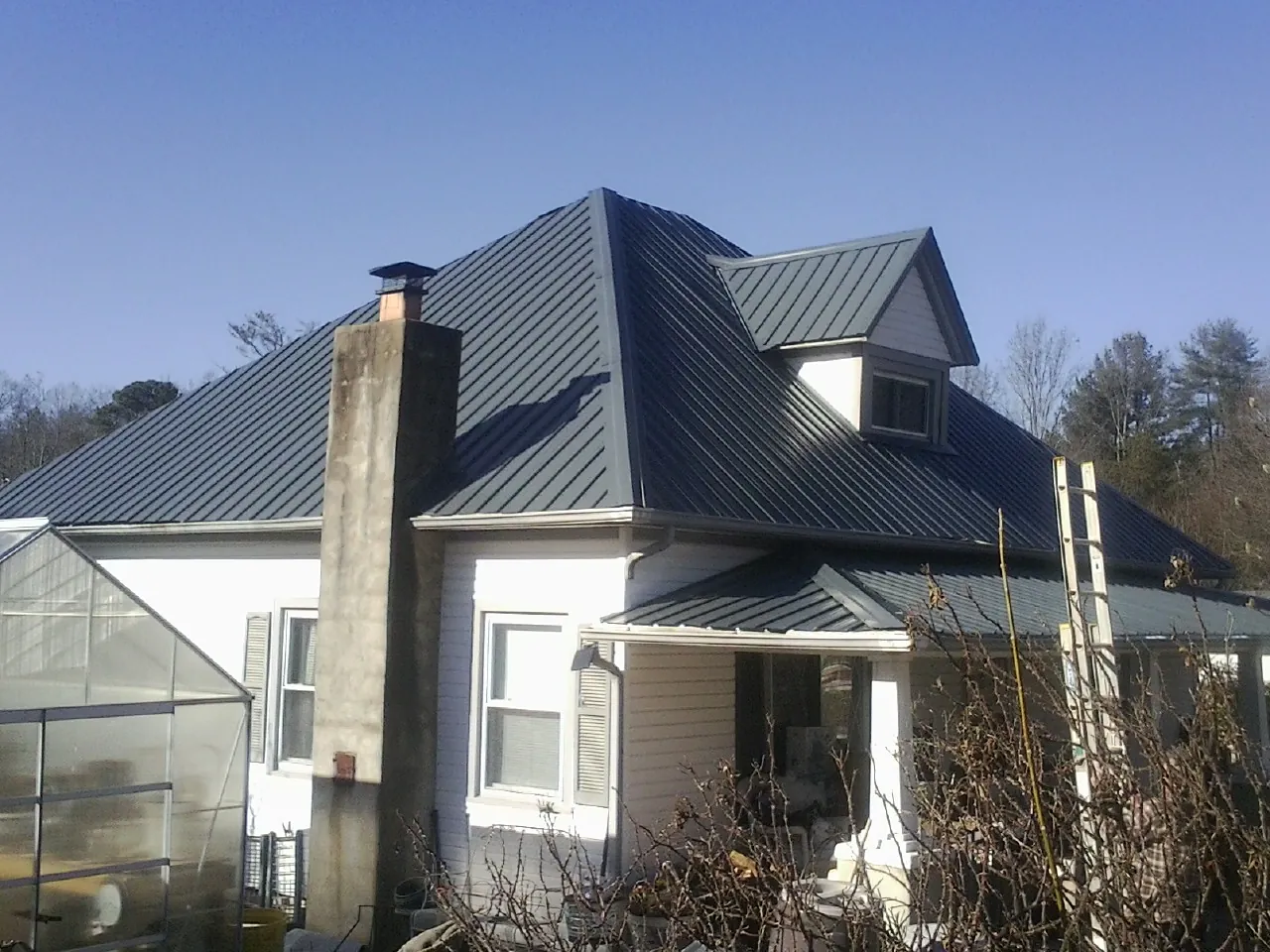 Dark blue standing seam metal roof on a white farmhouse with dormer — Slate & Tile Roof Repair by Roofing Brothers in Coupeville