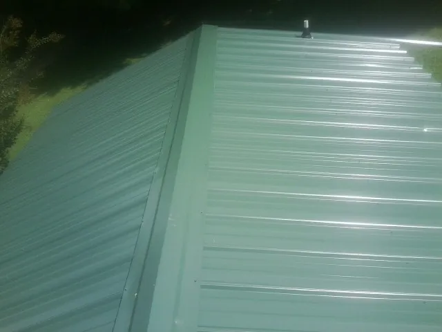 New green metal panels meeting at the ridge of a roof — Flat Roof Repair work by our crew in Coupeville
