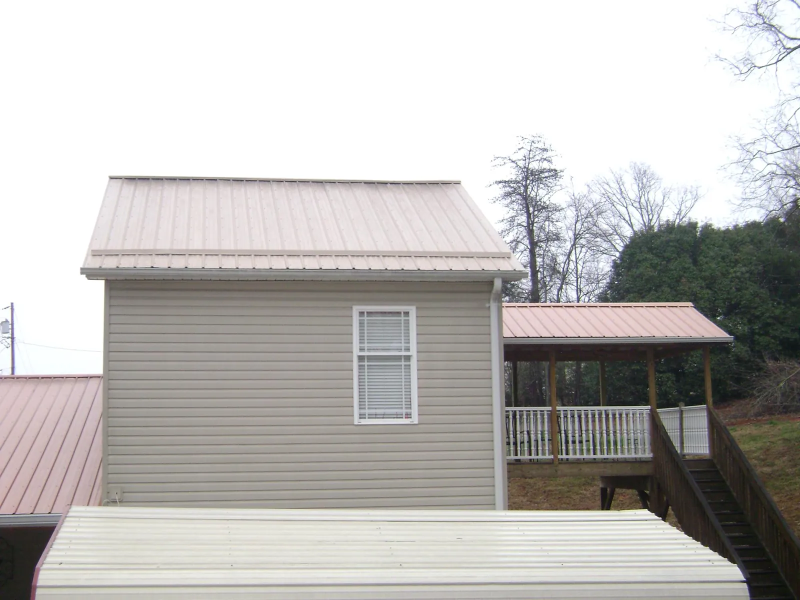 Tan metal roofs on a two story addition and attached porch, from a Roof Replacement job in Coupeville