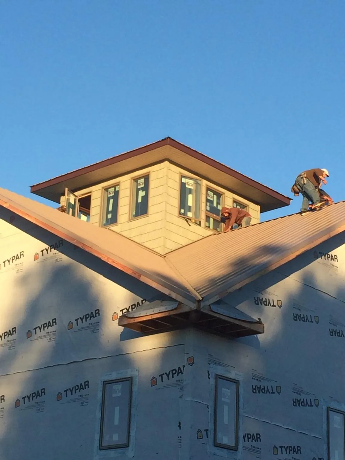 Roofers working around a rooftop cupola on a new metal roof at sunset — Roof Waterproofing in Coupeville by Roofing Brothers